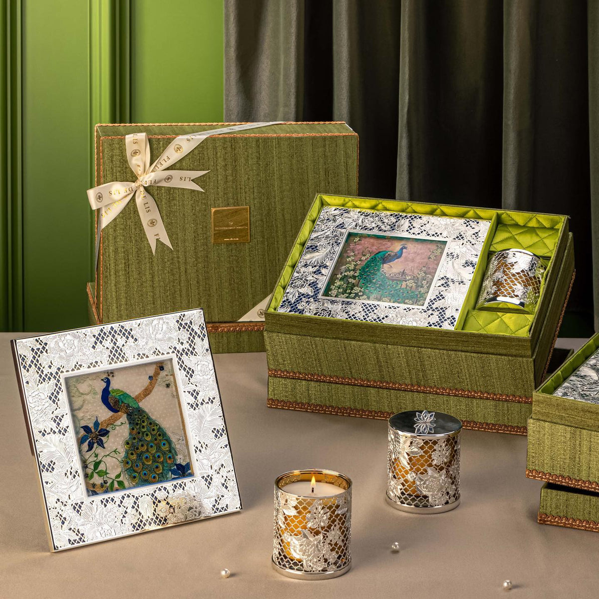 Decorative items including a framed picture, candles, and a box with peacock design on a neutral background.