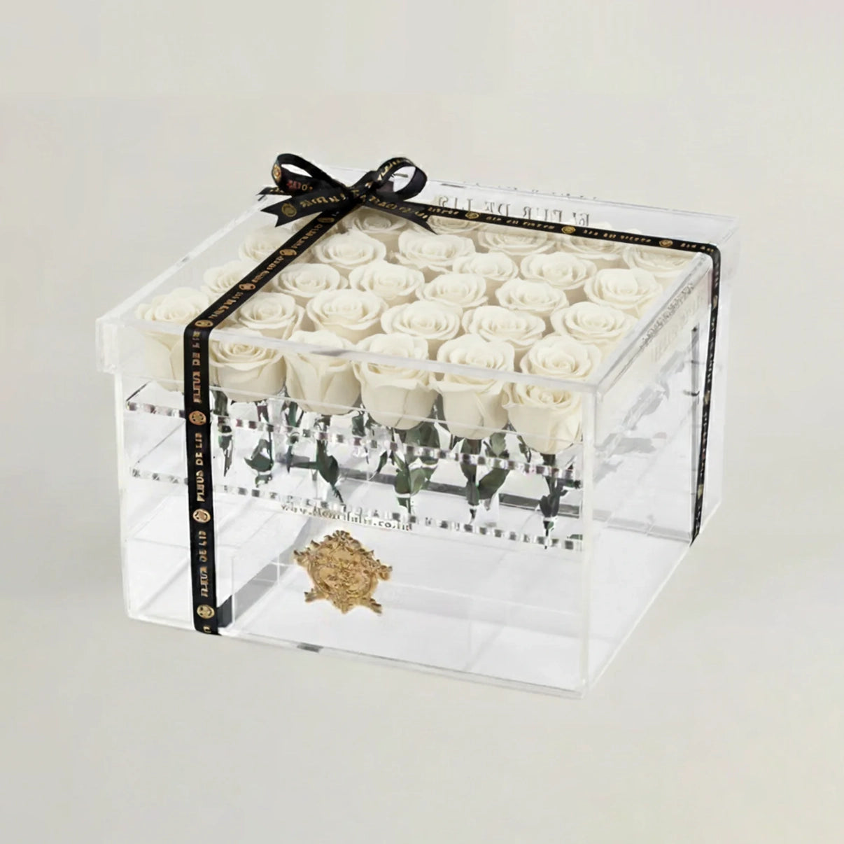 Clear box with white roses and a black ribbon on a light gray background