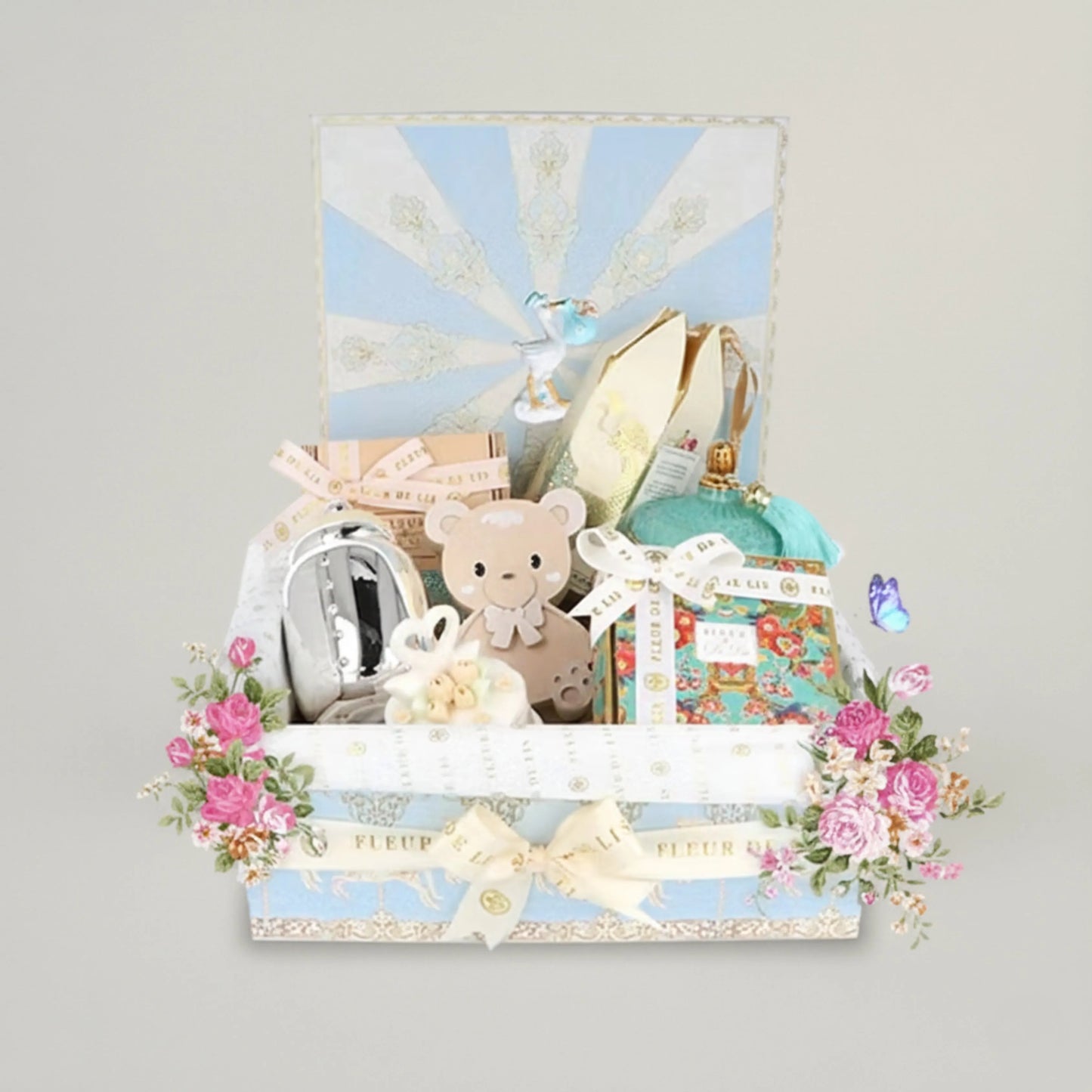Gift set with teddy bear, baby items, and decorative elements on a light gray background