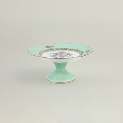 Mint green cake stand with floral design on a light gray background