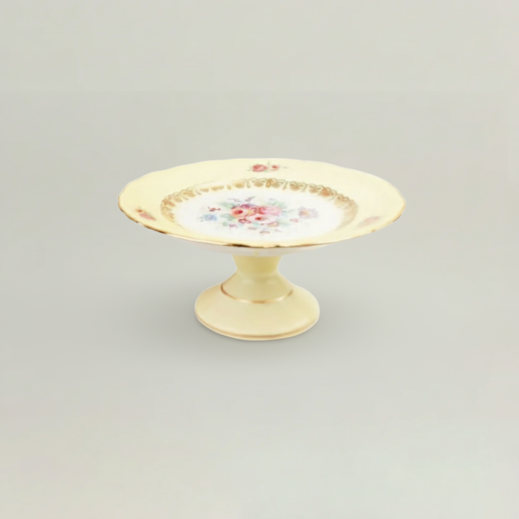 Decorative ceramic plate with floral design on a pedestal against a light gray background