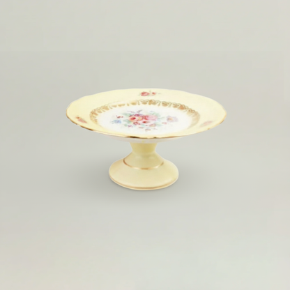 Decorative ceramic plate with floral design on a pedestal against a light gray background