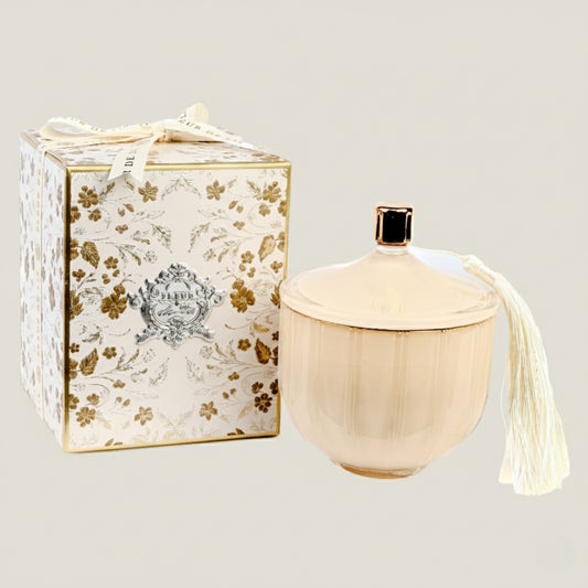 Decorative candle with tassel next to a floral-patterned box on a light gray background
