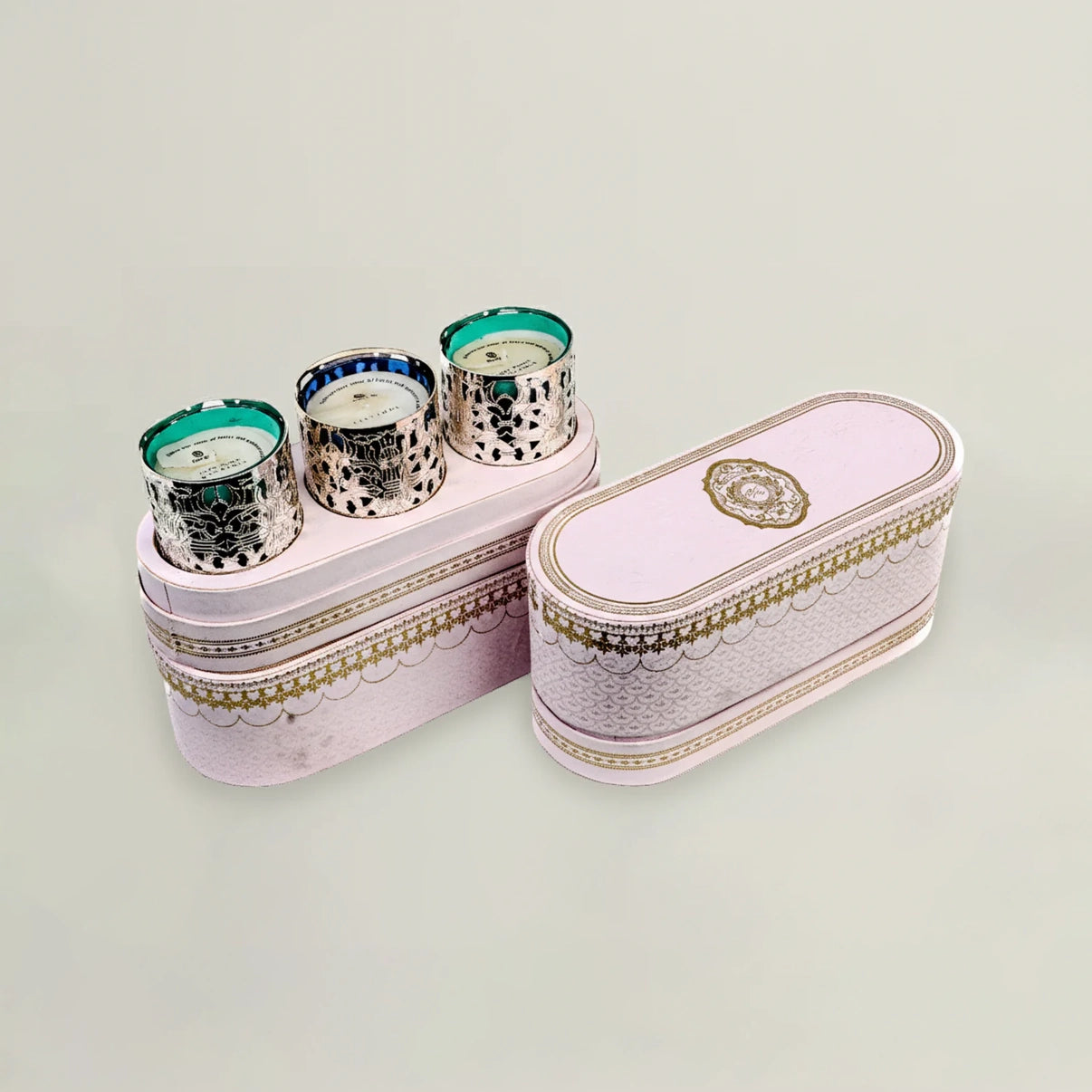Pink jewelry box with three decorative candles on a light gray background