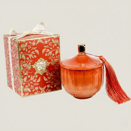 Orange decorative jar with tassel next to a matching box on a light gray background